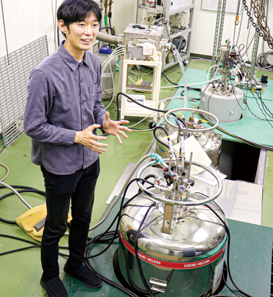 広島大学の自然科学研究支援センターで、絶対零度近くまで冷やすことができる冷凍機について紹介する志村准教授